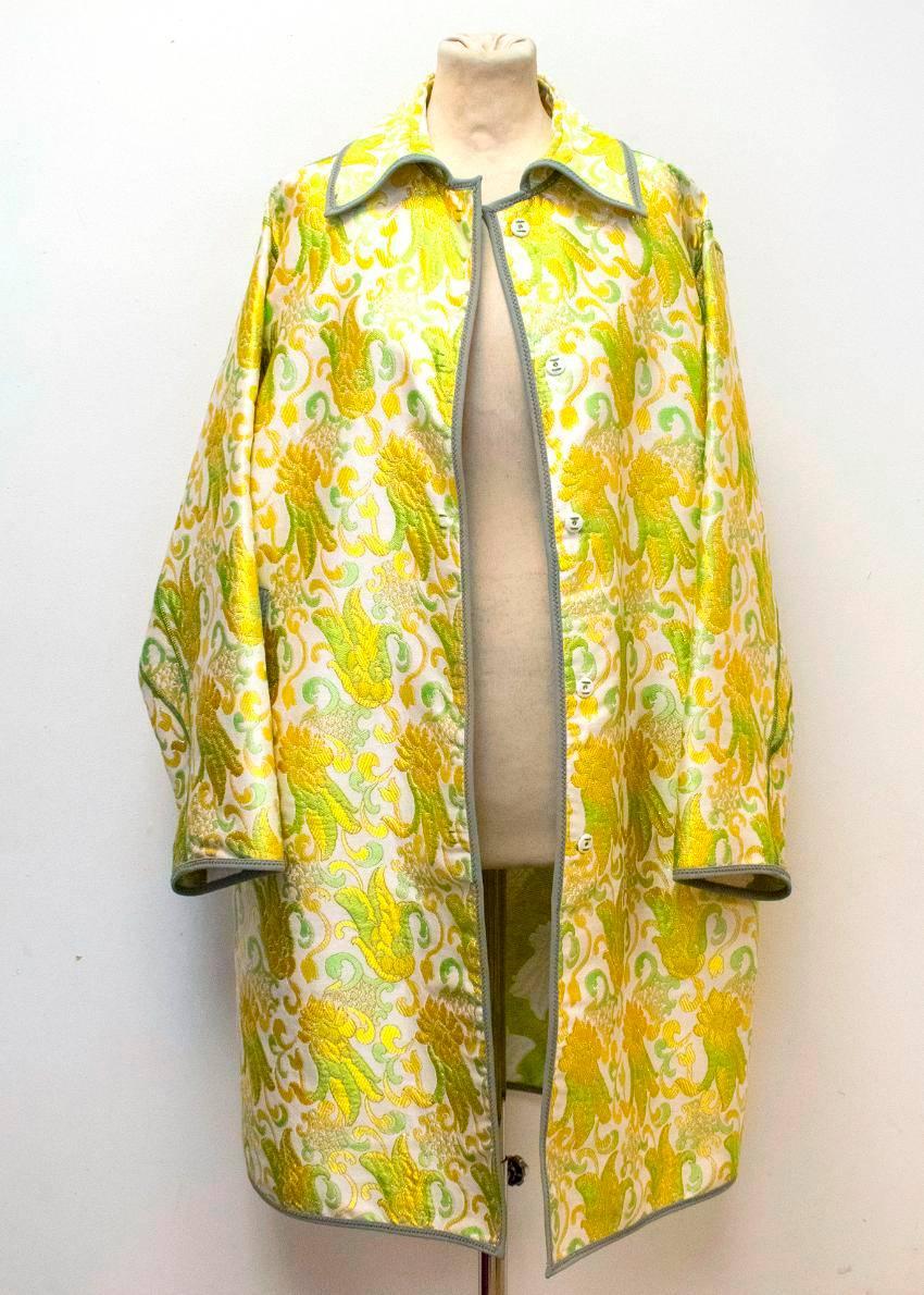 Prada cream coat brocade evening coat with yellow, green and gold floral print embroidered design. The loose fitted coat has grey scuba material on the edges of the coat. The coat has side pockets and hidden buttons on the inside of the placket.