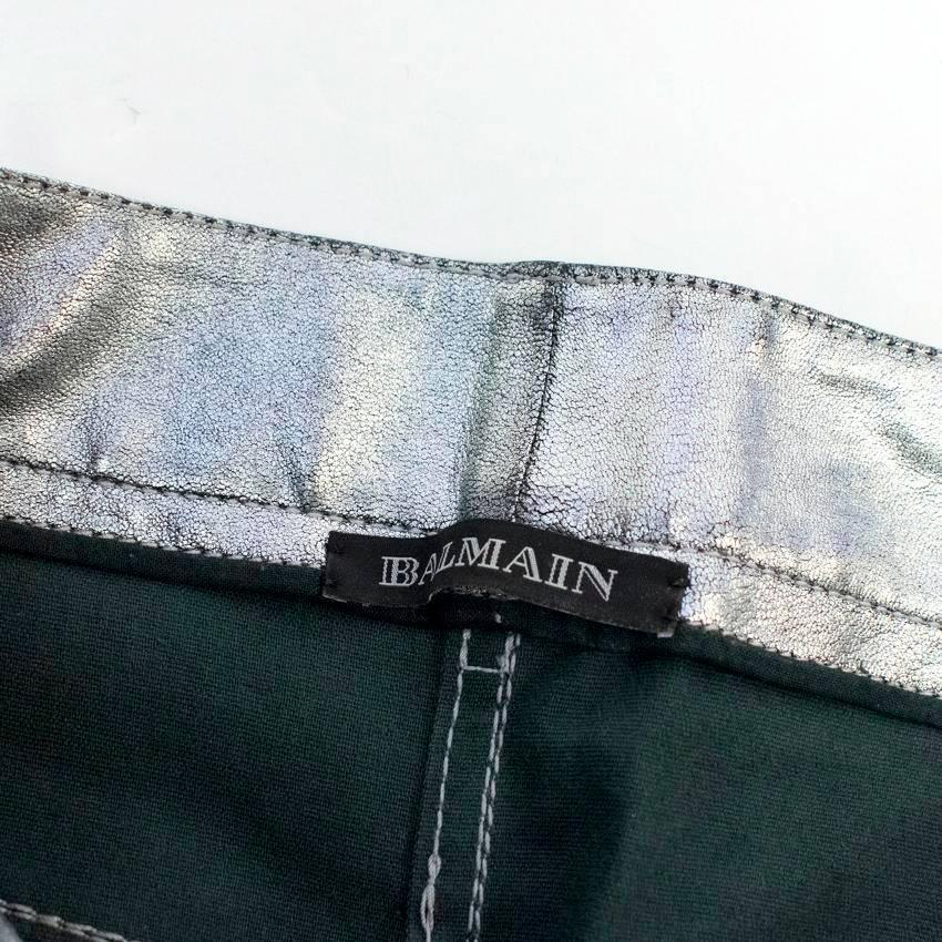 Balmain silver metallic leather motocross trousers with two zipper pockets at the back and front and three unzipped pockets at the front. 
The trousers are skinny fitting, midrise and feature stitched inserts on the knees. Fasten at the front with