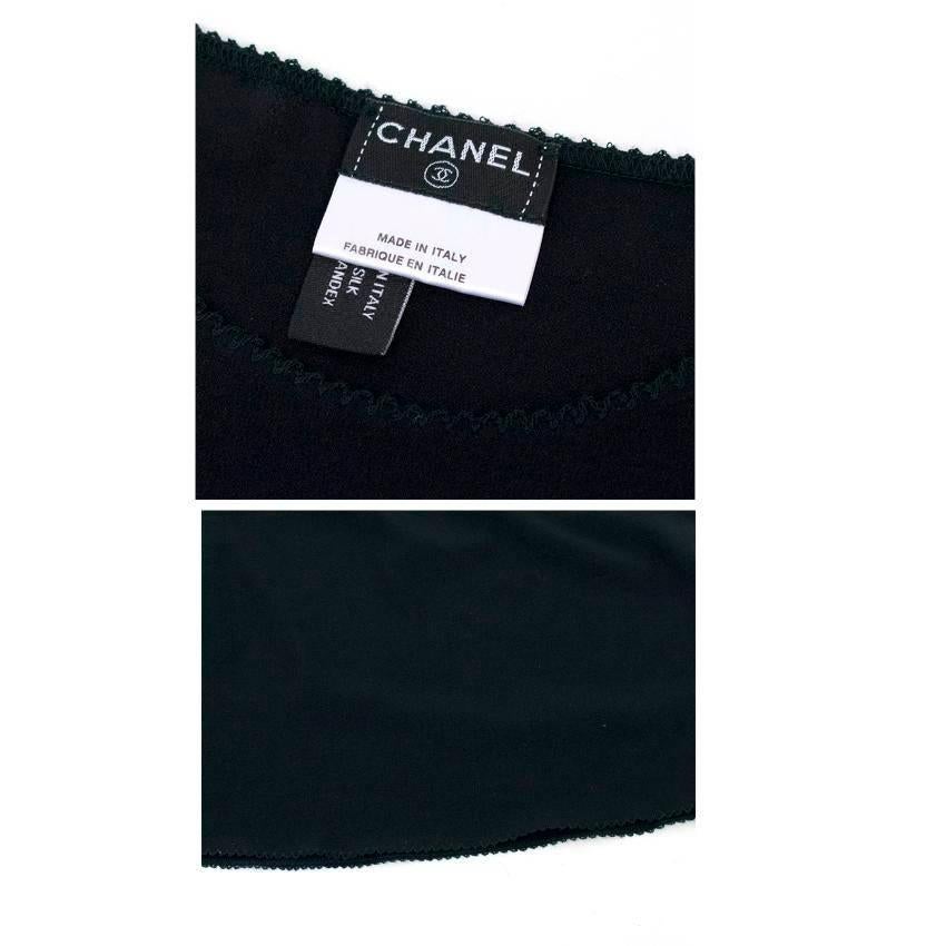 Chanel black sheer lace top with short puffed sleeves and a high neckline.
The top is lightweight and features frills on the cuffs, hem and collar. 
There is a flower decoration on the chest.
The top fastens at the back of the neck with three eyelet