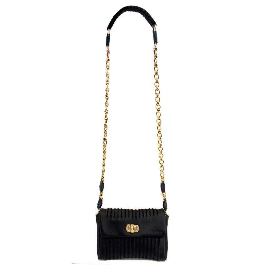 Nina Ricci black satin small cross body bag. Features, a front flap, textured ribbed detail, gold tone hardware, a gold tone chain body strap and a twist clasp fastening. Fully lined in pink leather. 

There in light wear to the material on the back