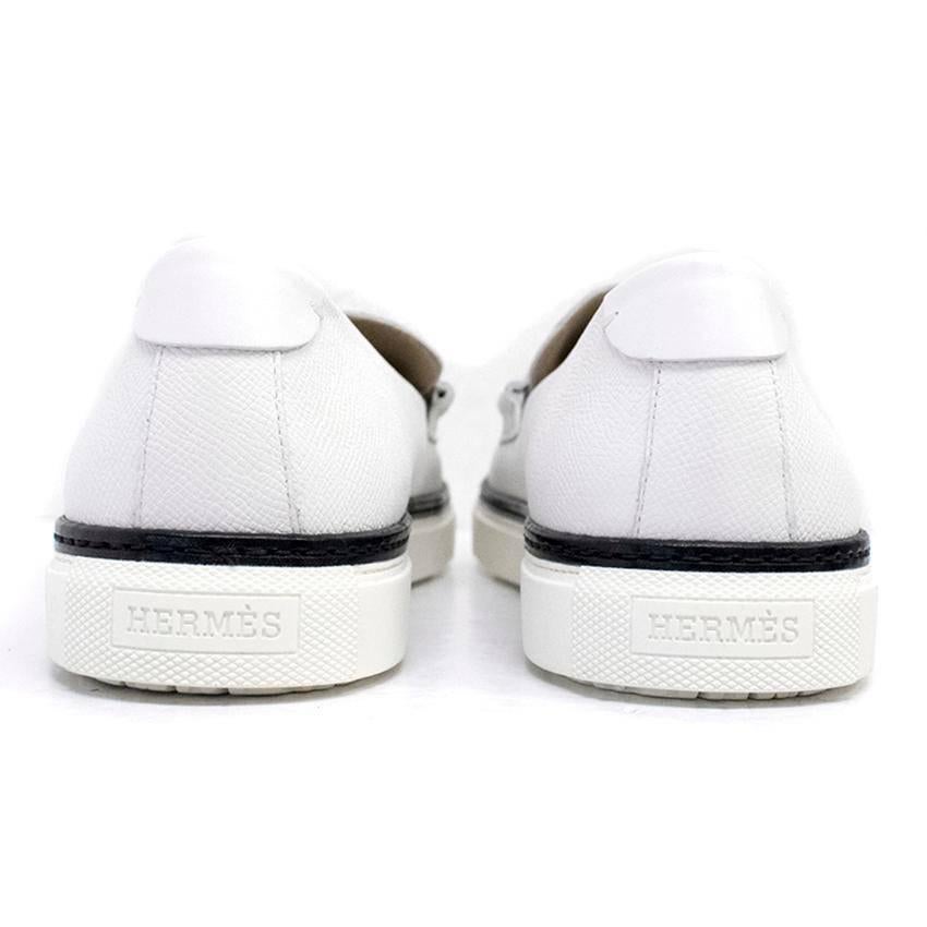 Hermes white loafers with rubber soles and black rim detail. Features the H tab attached to the front of shoe.

Size: US 11
Measurements: Approx: Length - 32cm Width - 11.5cm
Condition: 10/10