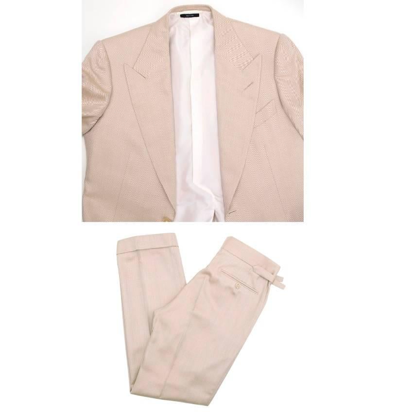 Tom Ford beige three piece suit featuring peak lapels, light shoulder pads and a two button closure on the jacket with one chest pocket and two front pockets. 

The waistcoat features a belted back and button fastening.The trousers have a straight