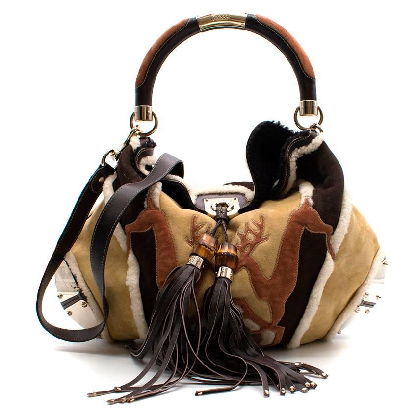 Gucci Shearling Large Indy Bag.

Beige and multicolor shearling Gucci Large Indy hobo with gold-tone hardware, leather trim, rounded top handle, tassel accents, tonal shearling interior and weighted closure at front. Includes leather zip