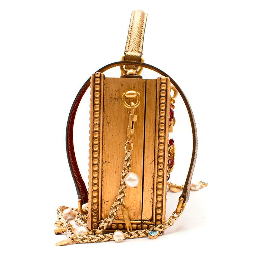 Dolce & Gabbana Embellished Box Bag

Stunning jewel of a bag which would look beautiful as a showpiece!

- Antique gold-tone wooden frame
- Metallic gold textured leather handle and trims
- Removable crossbody chain strap with charm details
- Suede