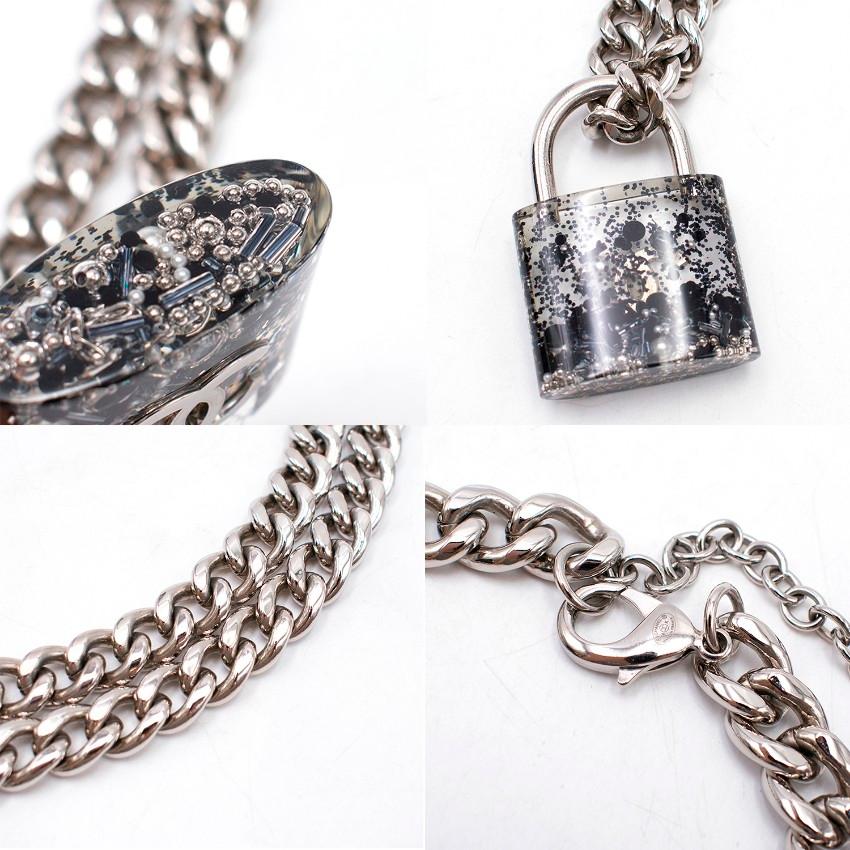 Chanel Silver-tone CC Padlock Necklace

- Large clear resin padlock withsilver-tone hardware and the interlocking C's, filled with black glitter and beads.
- Large, chunky silver toned chain with a large lobster clasp
-  Comes in an authentic black