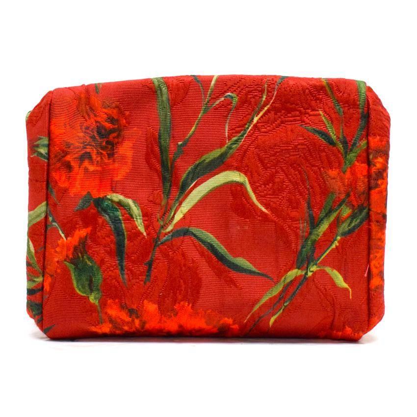 Dolce & Gabbana red floral clutch bag with an emerald-cut jewel-embellished opening in the middle of the bag. The bag has a magnet holding the bag closed, and a small side pocket on the inside.

The bag has a small white mark on the bottom of the