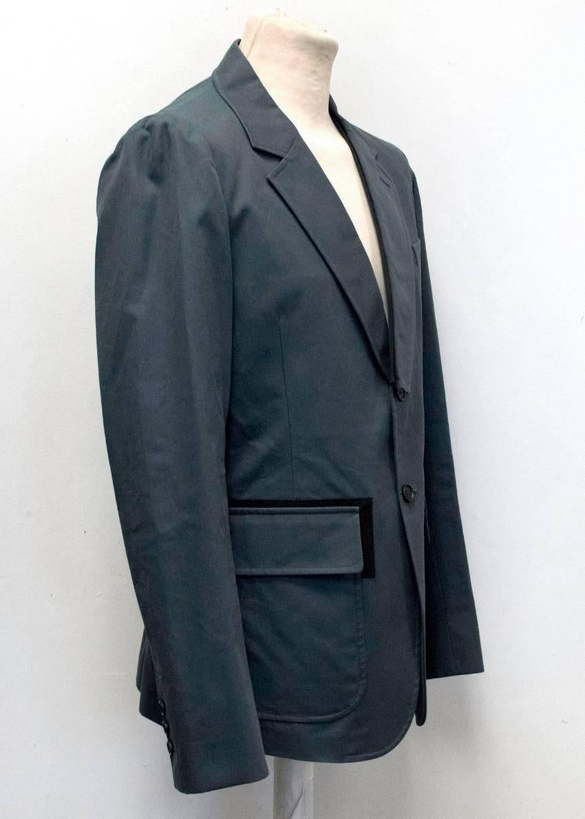 Alexander McQueen two piece navy suit. The jacket features a notch lapel, three exterior pockets. The lapel and pockets are trimmed with black cotton. The jacket also features a single vent and is partially lined. 
The trousers are tapered and have