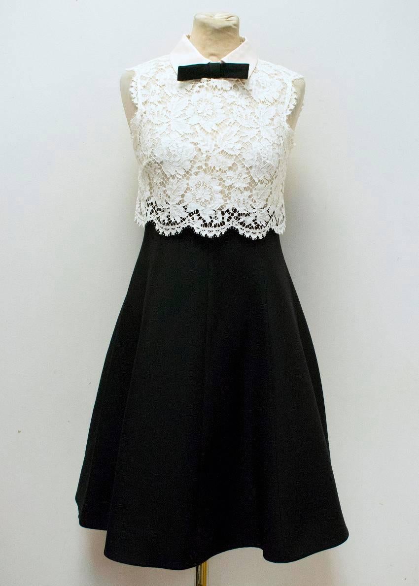 Valentino Spa white lace and black dress. This dress has a white collar and a black bow in the center. It is sleeveless with a white lace overlay. The bottom half of the dress is black and fully lined. At the back of the dress, there is a concealed