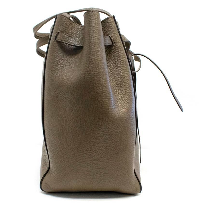 Celine cabas phantom tote in taupe with a leather tie at the top. It also features a suede interior and two pockets and a zipper pocket on the interior.
Condition: 10/10

Approx measurements: 
Width: 50 Cm 
Length: 31 Cm 
Depth: 31 Cm 
Handle