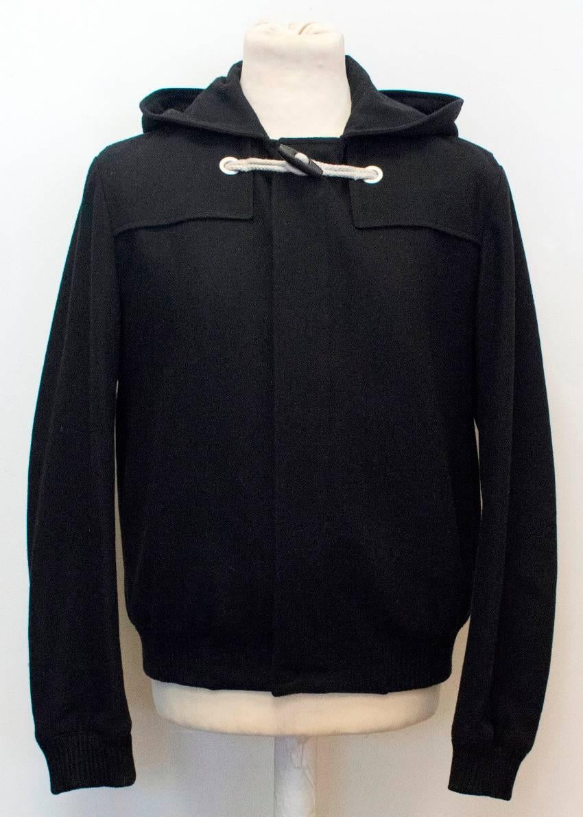 Dior men's, medium weight black wool bomber jacket with a hood, side pockets and rope ties around the collar with a toggle button.

Approx measurements: 
Shoulders: 46 Cm 
Sleeves: 67 Cm 
Chest: 46 Cm 
Waist: 48 Cm 
Length: 68 Cm

100% Wool

US size