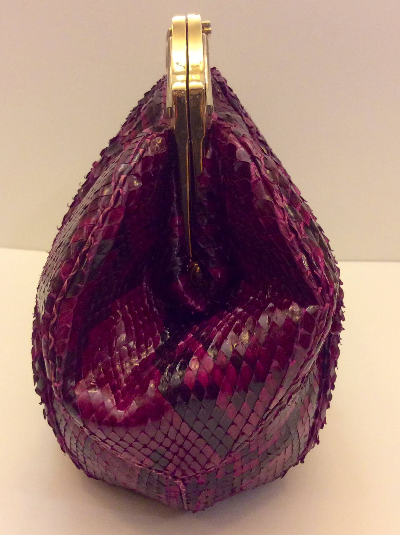 This is a gorgeous Judith Leiber clutch with optional gold chain. The handbag is composed of a striking magenta snakeskin and features gather details. There are two interior zipper & slot compartments and snap closures. This purse was hardly used,