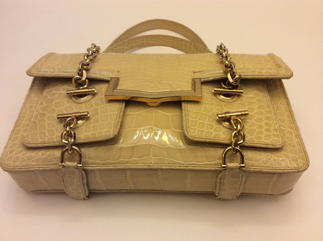 This is a stunning Judith Leiber buttercream crocodile flap handbag with two exterior front pockets. Gold heavy toggle chains with crystal cabochon. 
Two crocodile handles.  Exterior back slot pocket compartment. Hot pink suede leather interior