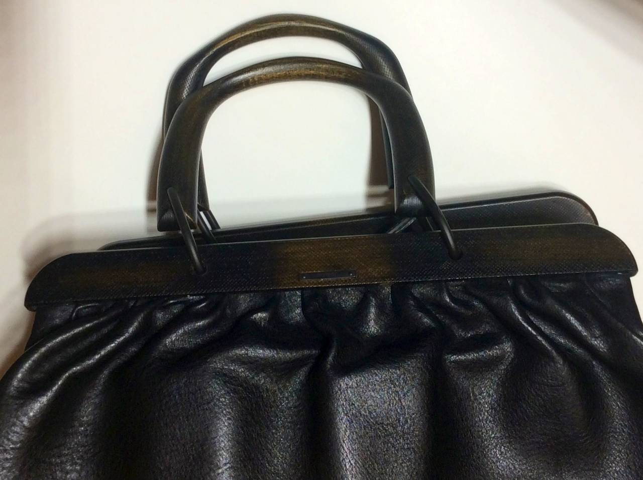 This is a vintage Tom Ford designed for Gucci durable black leather handbag with wood trim and handles. Interior leather flaps with buckle closure.
Pristine condition. 
Measurements approximately 16 x 10 x 6