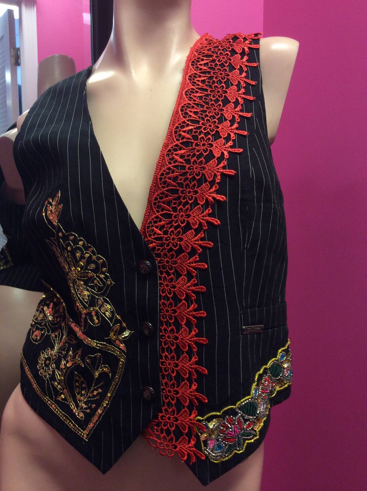 This is a rare John Galliano black and white pinstripe vest.  It has beautiful red embroidery on front left and gold sequins floral pattern on right. The back has Lasage embroidery and sequins forming a fun array of hearts and floral pattern. 
Silk