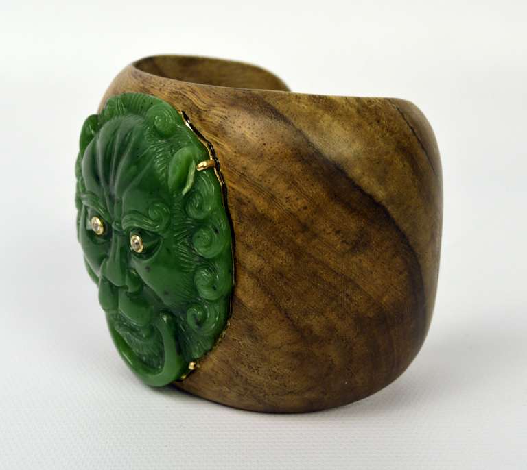 If unique is what you seek…..Curved Teak open ended 2 1/2 inch cuff bracelet adorned with a large carved Spinach Jade lion’s head (2 1/4 H x 2 1/4 W).  Setting is 14 karat yellow gold.  Bezel set brilliant cut diamond eyes.  Curved opening measures
