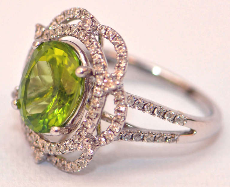 Stunning 14 karat white gold ring boasting a 4.89 ct oval peridot.  Accented on the split shank and surrounding the peridot are micro pave brilliant cut diamonds with a total weight of 1.10 carats.  Uniquely feminine.  Sits low on the hand for