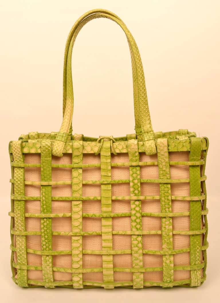 This Nancy Gonzales bag has a lime green python leather open weave exterior with a beige linen interior bag. The closure is a leather loop that fits over the leather knob. Inside, the bag is divided into two interior sections by a zipping interior