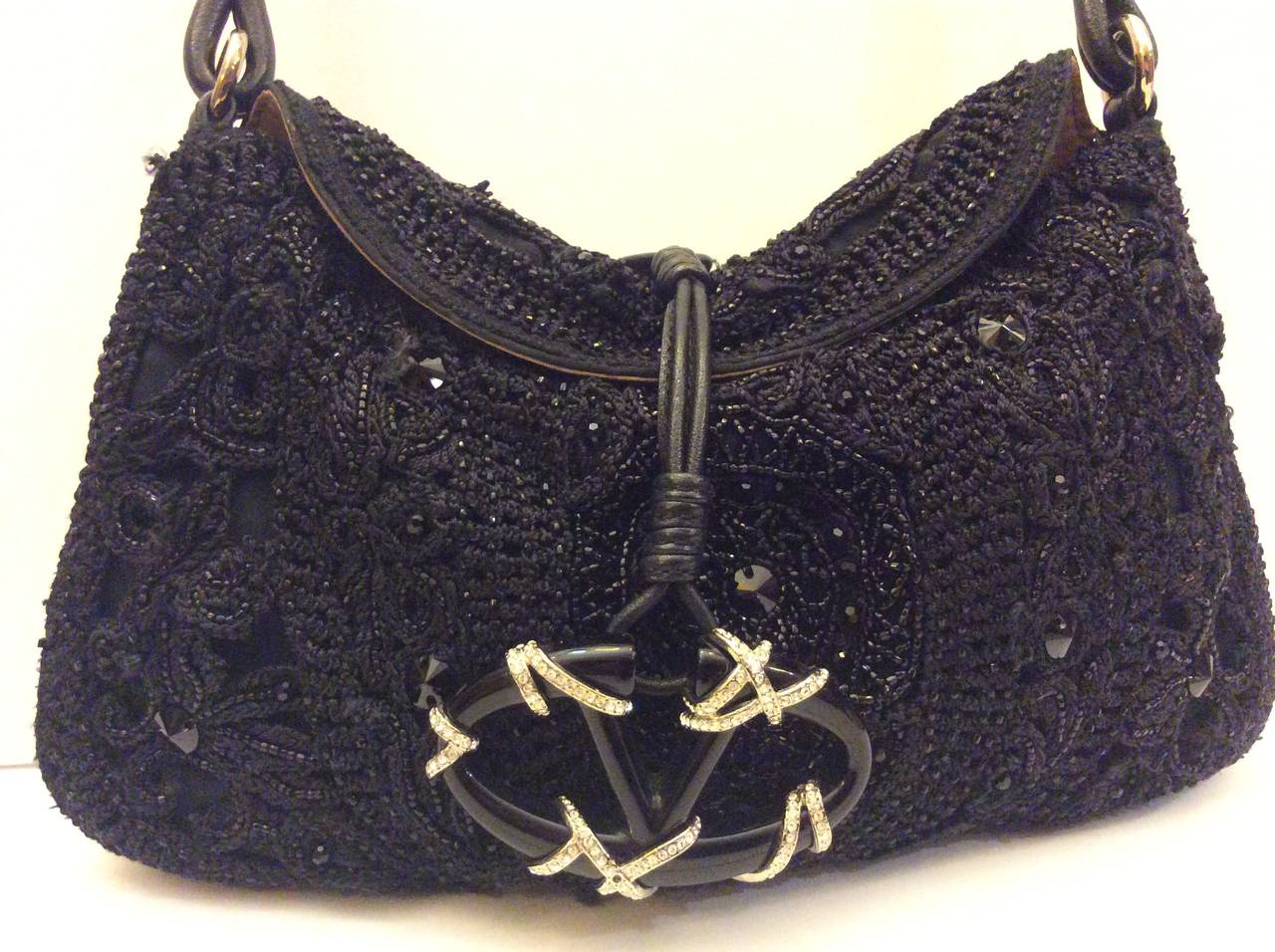 This is a stunning Valentino Garavani Black silk crochet embellished with beaded sequins and crystals evening handbag. Minimal flap closure with classic leather strap and traditional large V toggle encrusted the crystals. 
Beige silver lining with