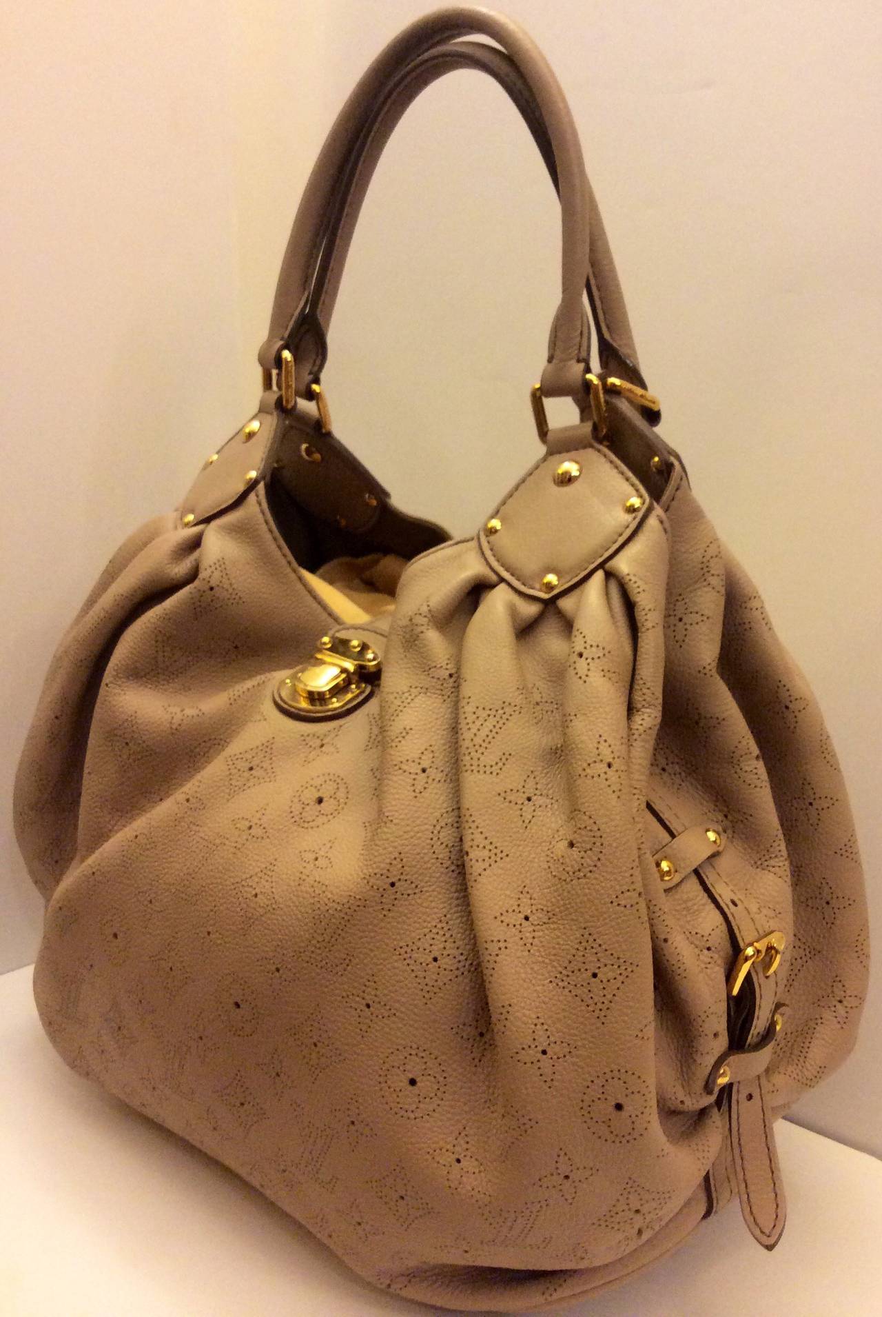 This is a LOUIS VUITTON Mahina L in Coquille. This stylish Louis Vuitton shoulder bag is created from loose and relaxed soft beige leather that is gathered at the top corners for a characteristic look with a perforated Louis Vuitton monogram. The