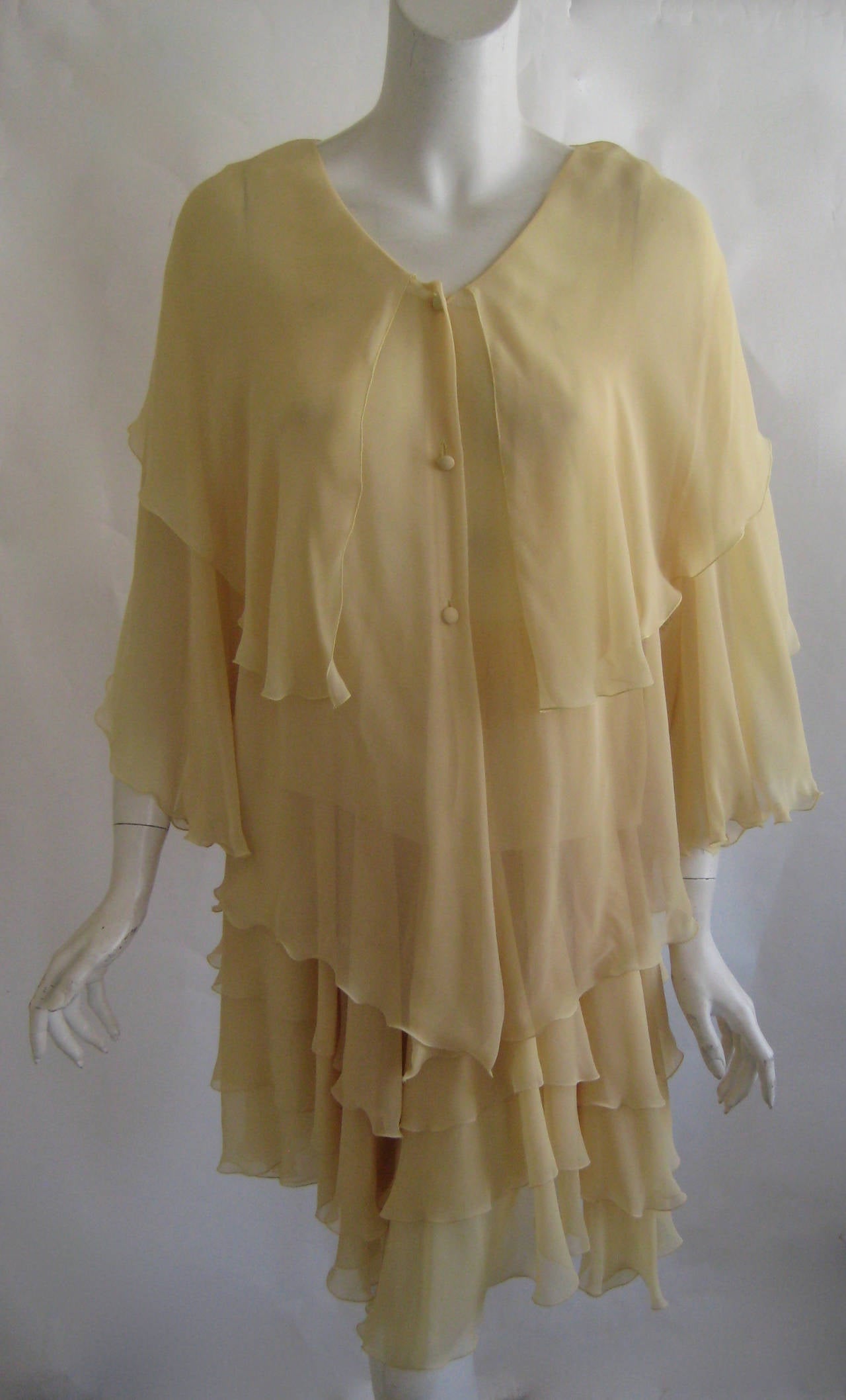 3 piece Azzaro ensemble made form 100% silk chiffon .
This consists of a sheer sleeveless tank and an overblouse that buttons down the front with silk covered buttons .The blouse has an attached silk caplet and the skirt is 3 layers of silk