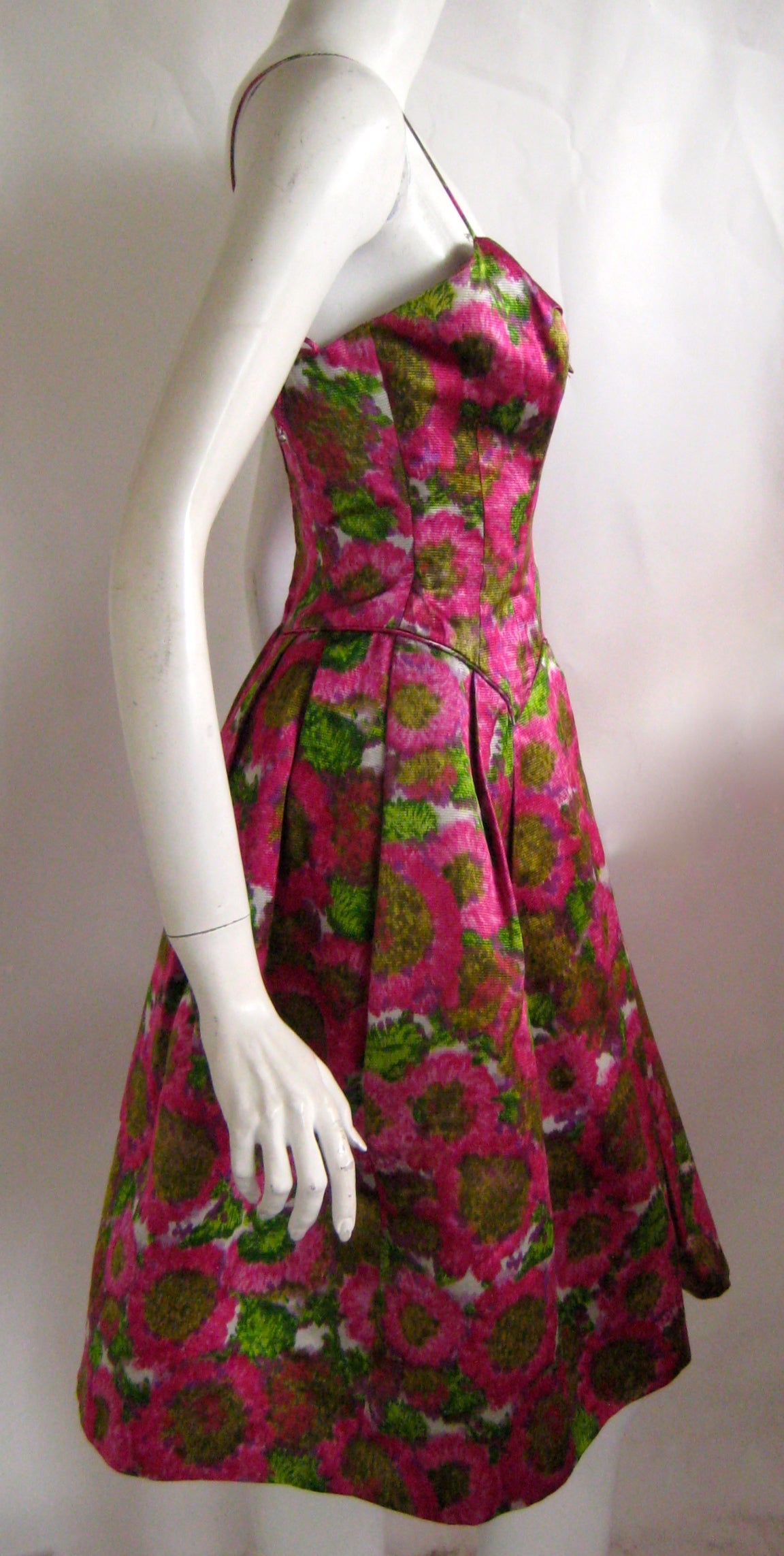 Lovely little silk floral cocktail dress by Frank Starr.This has thin spaghetti straps and it zips up the back with a metal zipper.The skirt is structured and stands on it's own without a crinoline .It has a boned shelf bust.This Frank Starr