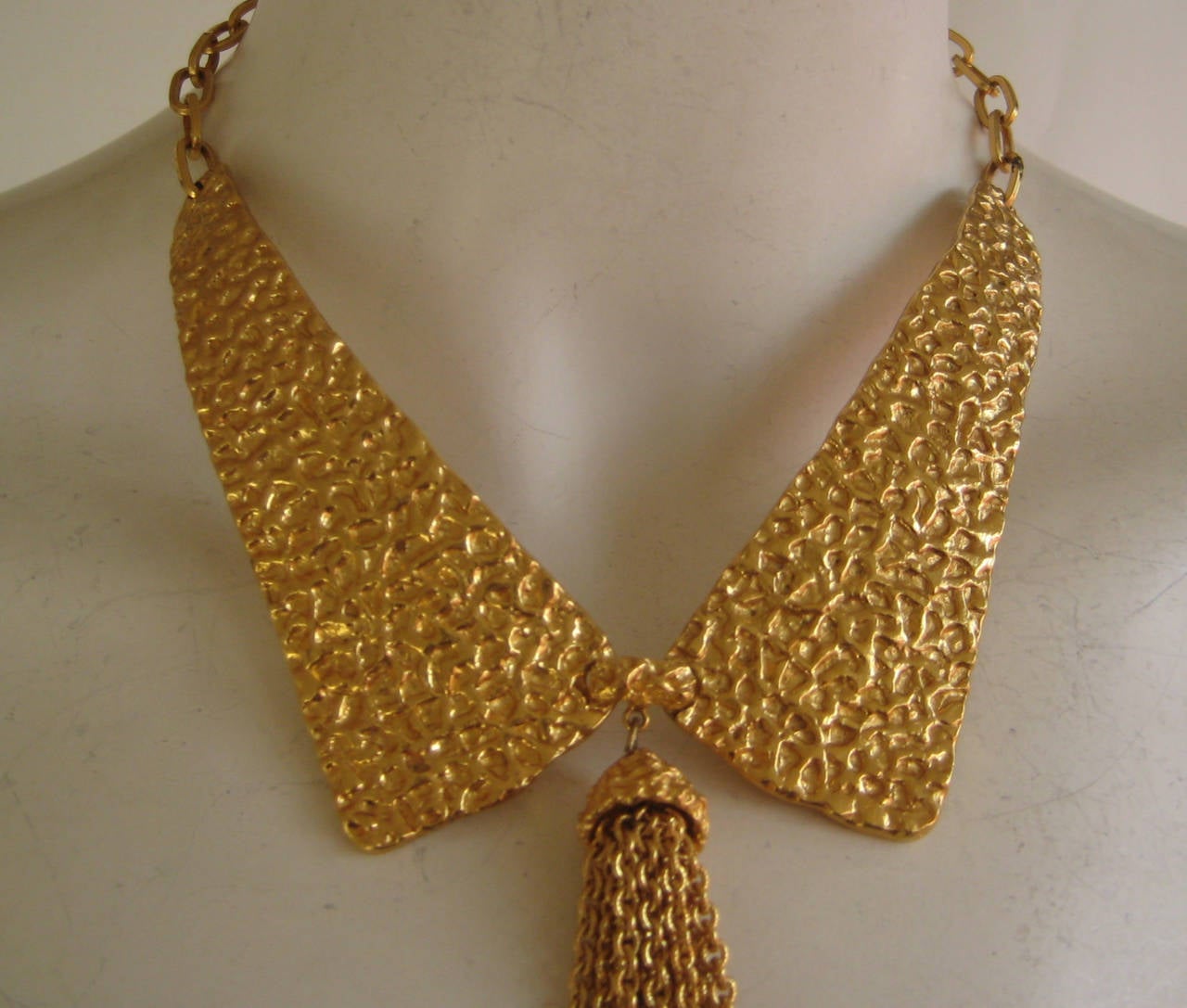 Bold gold tone statement necklace with two metal plates attached to gold link chain.Long chain fringe at the center front .Excellent condition with no signs of wear.Necklace is signed Trifari  on the hook clasp.Each plaque measures 4