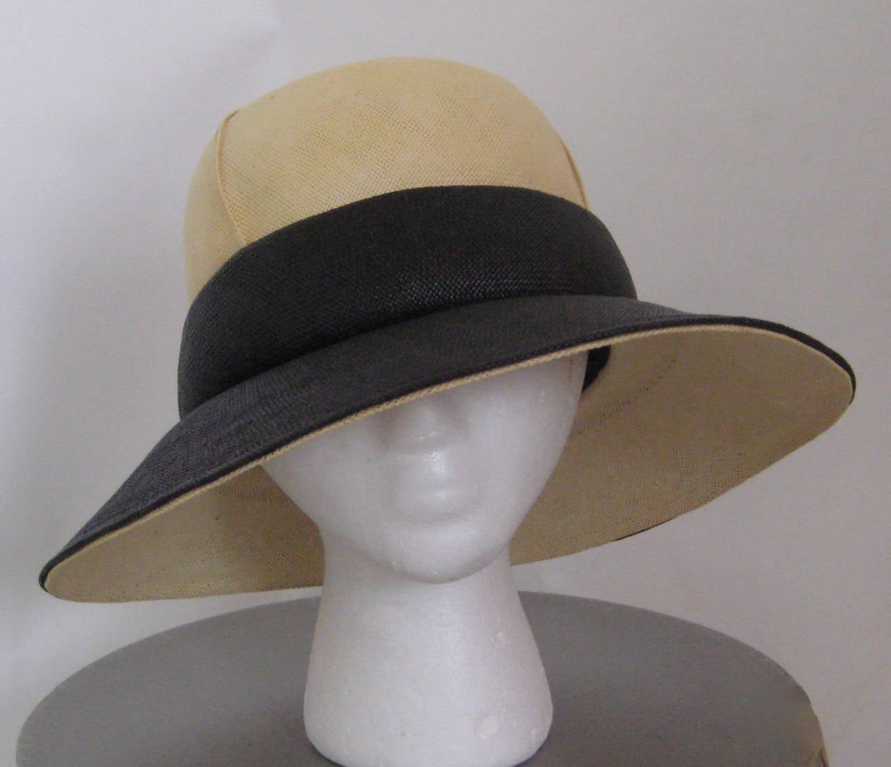 Darling 1960s Christian Dior straw hat.Wide black brim and natural color crown.Interior grosgrain petersham and elastic chin strap.There is some color variation to the natural straw crown but this is most likely original to the piece and it does not