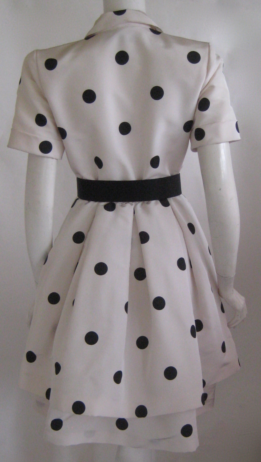 Wonderful 1980s cocktail party dress in silk taffeta with an attached silk organza crinoline that is edged in the same polka dot taffeta as the dress.This dress has small shoulder pads and a matching black silk belt.It snaps up the front and it has