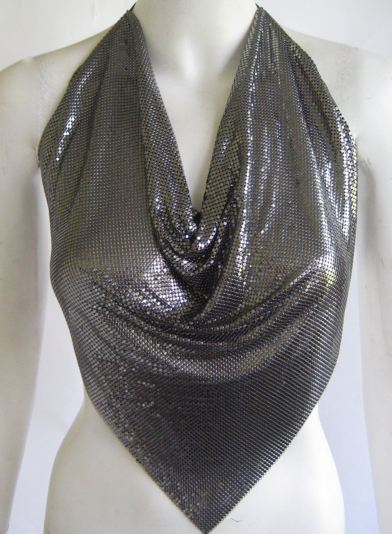 Killer metal disco top in a beautiful gunmetal mesh
This ties with leather ties at the neckline and waist .Top drapes and is cut in a point on the bottom .This is in  excellent condition and bears no label.
This top measures 19
