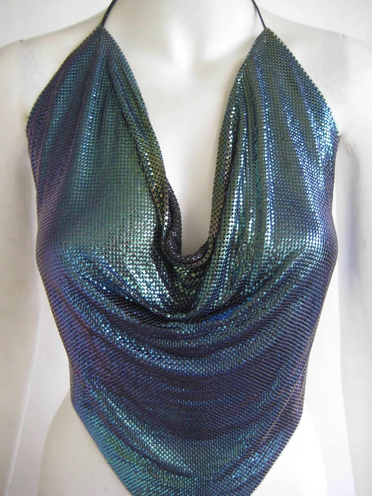 Killer metal disco top in a beuatiful iridescent mesh that shifts form blue to green.
This ties with leather ties at the neckline and waist .Top drapes and is cut in a point on the bottom .This is in very good condition and bears no label.One of