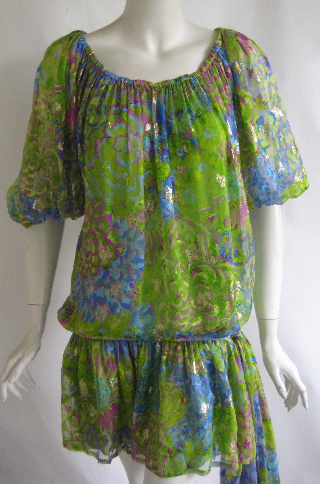 Yves Saint Laurent peasant dress of metallic silk chiffon .Completely lined in green silk chiffon.Elastic at neckline and hips .Chiffon swag to one side can be tired in a bow. 80% silk 20% metallic.
Size 38.