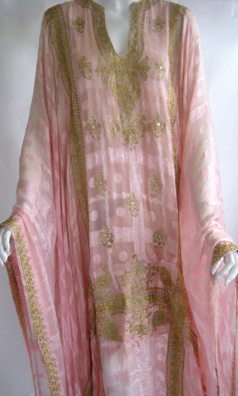 Exceptional pink silk caftan that dates to the 1920s 
Brocaded semi sheer silk
Slight train in back
Decorated with gold chain stitch embroidery and tiny gold sequins
This is cut in a t shape with wide cuffs that are floor length and it has