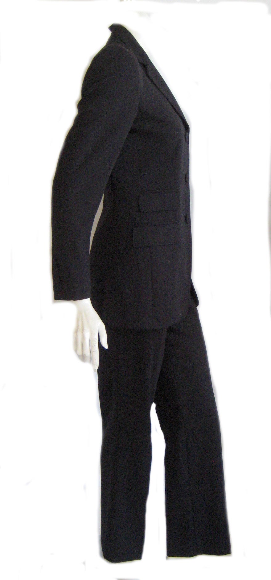 Pinstripe trouser suit in black wool with a fine blue stripe .Jacket is 100% wool  lined in rayon acetate combination .High waisted pats have a side zipper and one button.Jacket has double pockets that are still uncut and it fastens down the front