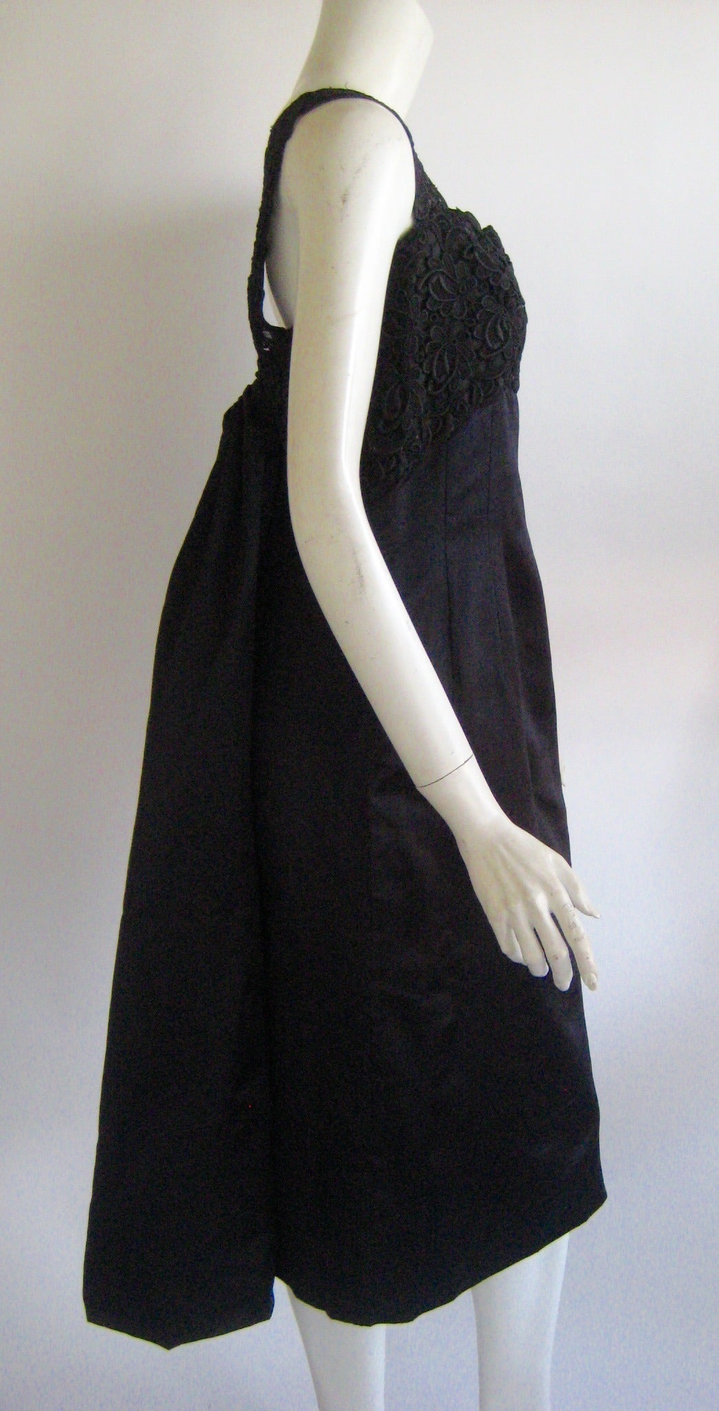Lovely black silk cocktail dress with eyelet bodice and attached back drape that comes to a bubble shape at the bottom .Truly wonderful design .This is made of a lustrous silk and fine cotton eyelet and it looks as if it was worn very little if at
