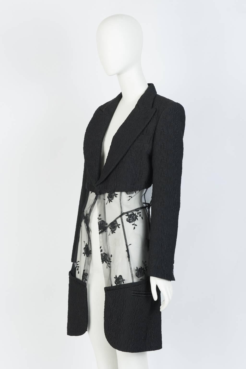 Fitted blazer coat in embroidered silk with peak lapels, slash pockets, 3 button cuffs, and sheer panel of rose-patterned mesh. 