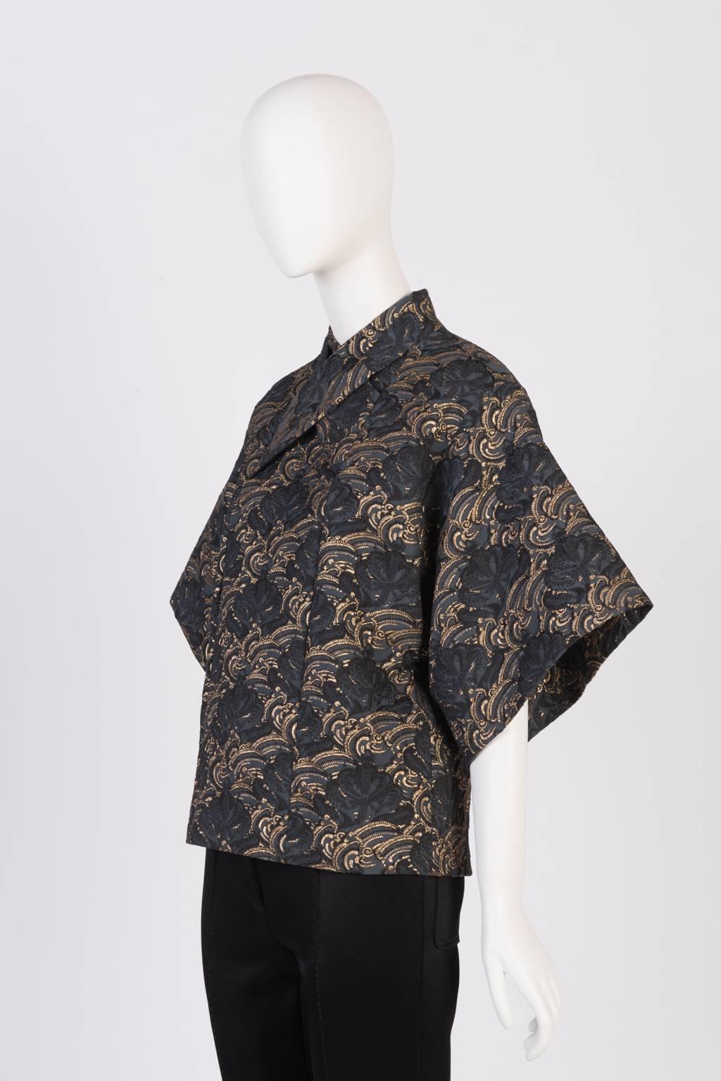 Fitted wrap top in lightweight, gilt-edged floral pattern features elbow length kimono sleeves, Mandarin collar, and back zipper.