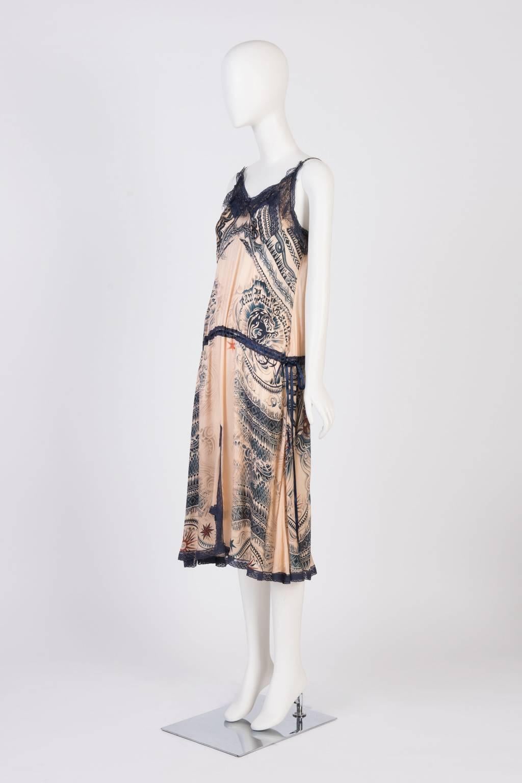 Iconic Jean Paul Gaultier tattoo print silk lingerie dress with navy lace trimmings. Adjustable shoulder straps and silk ribbon draw-string through lace panel at waist. 