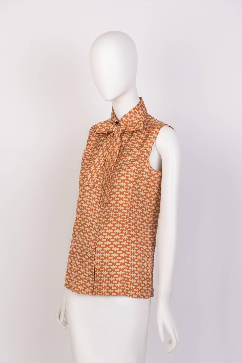 Sleeveless silk blouse with subtle H print, front pockets, and detachable collar bow.