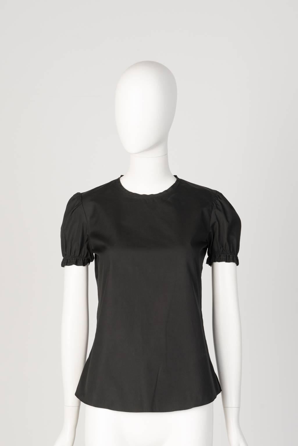Black cotton blouse with gathered cap sleeves, slit sides and button closure at back of neck