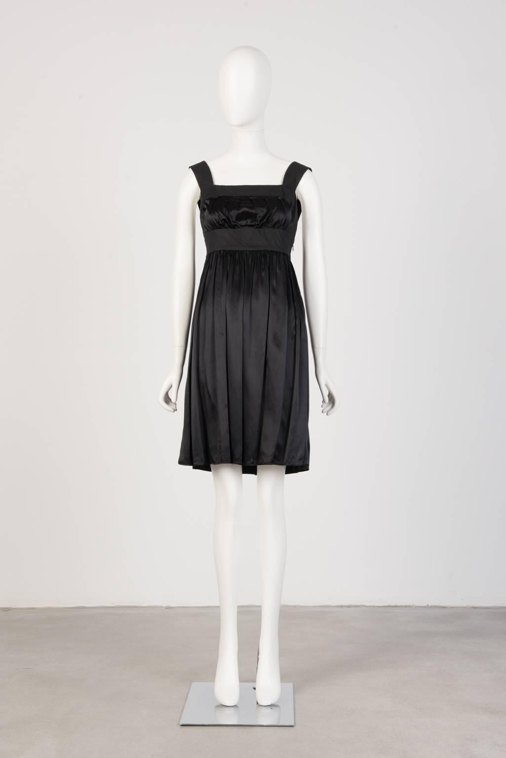 Black, open back, knee length dress in satin-like viscose with empire waist, pleated skirt and cotton-edged bodice and straps.