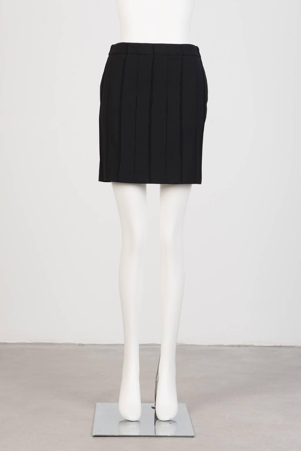 Black mini skirt in slight stretch wool with slash pockets and closed pleats.