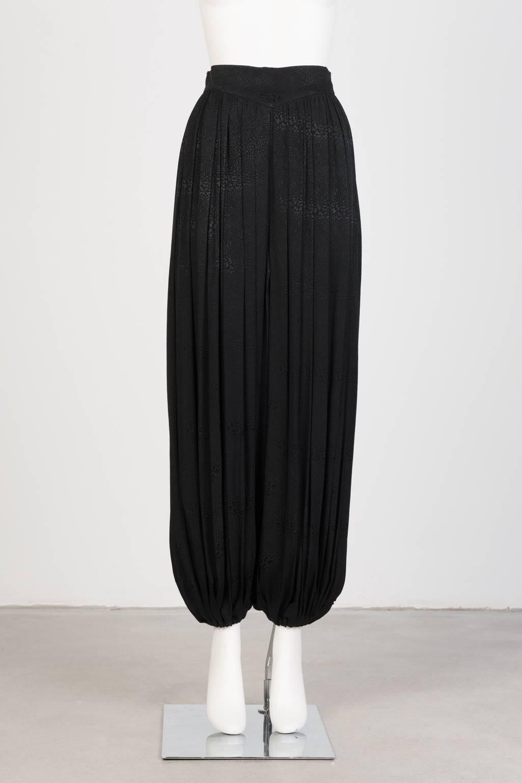 Black harem pants with gathered cuff and zip closure in finely pleated, subtly printed, jacquard.