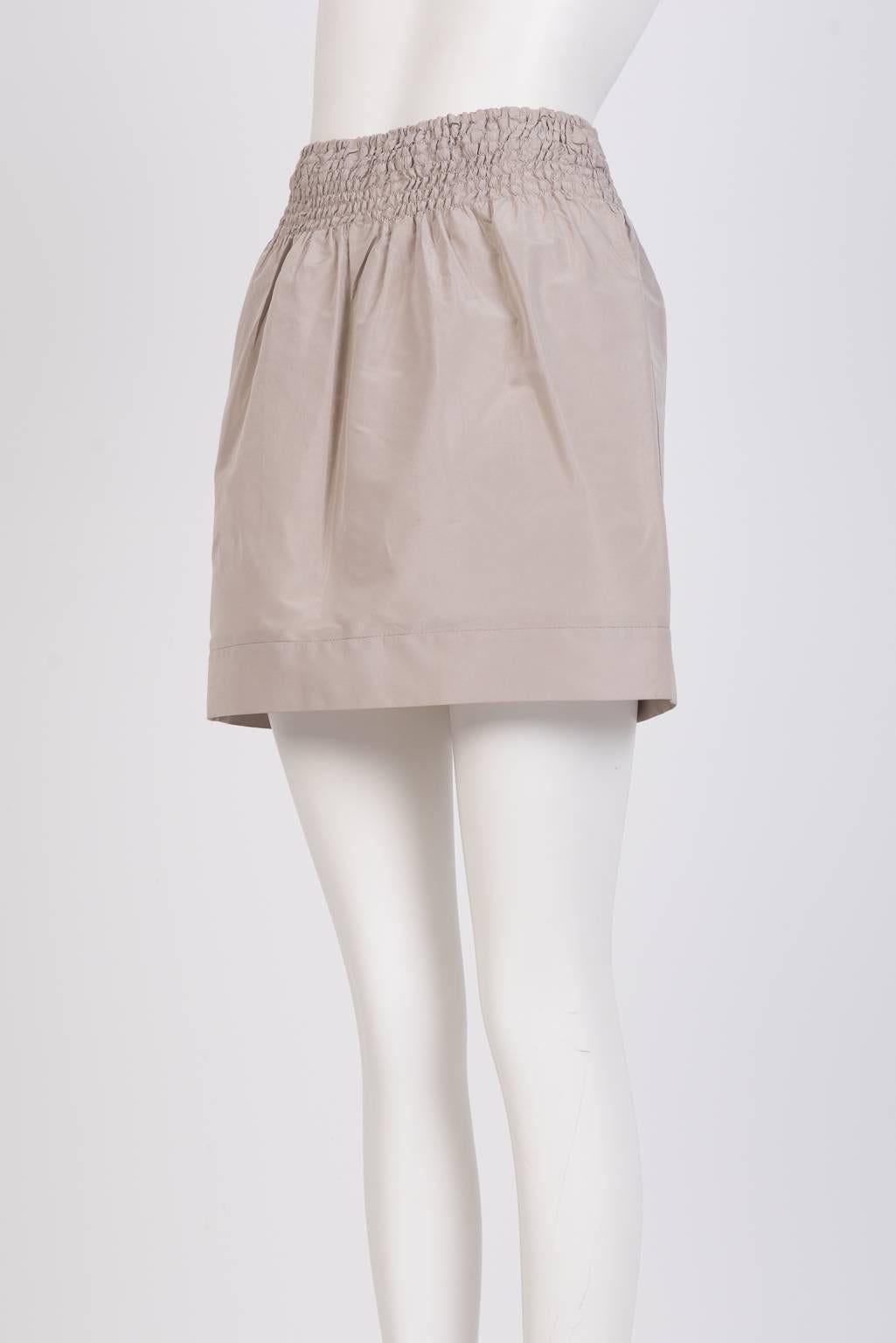 Short full skirt in futuristic technical fabric with a wide smocked waistband 