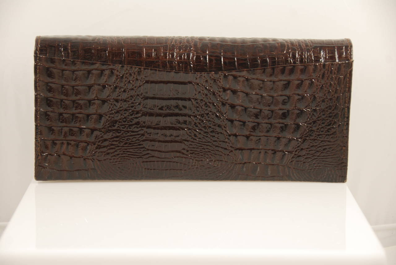 Pierre Cardin brown alligator clutch from the 1970s. Lining is pigskin suede is a tan color.  Clasp in a pin clasp that works well an d the bag closes securely. There is one main compartment and a second compartment that closes like a change purse.