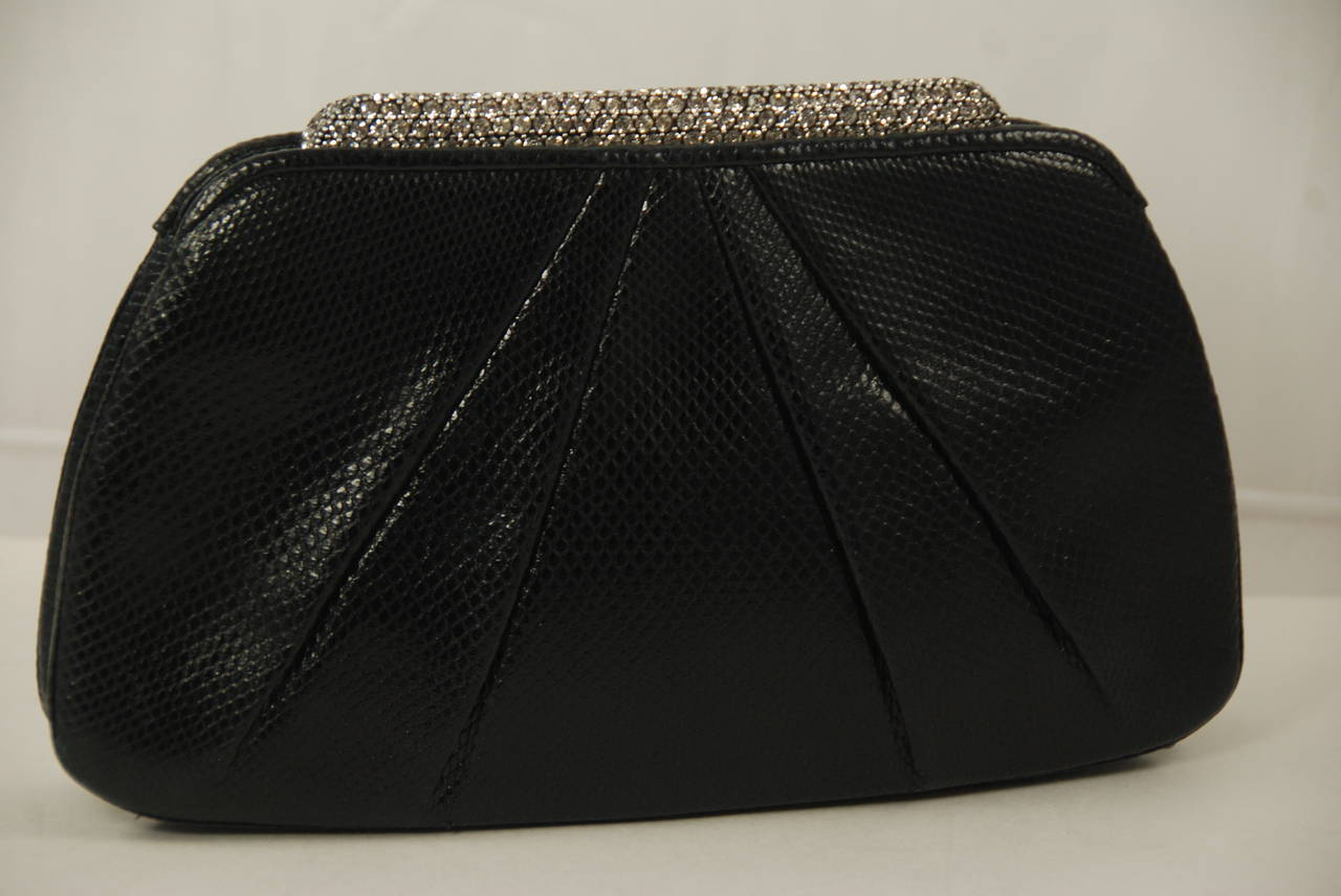 Black karung (lizard) Judith Leiber evening bag/ clutch with a rhinestone bar clasp that runs across the top of the bag. To open the bag you press back on the bar. Clasp works well and bag closes securely. Inside is lined in black satin and there