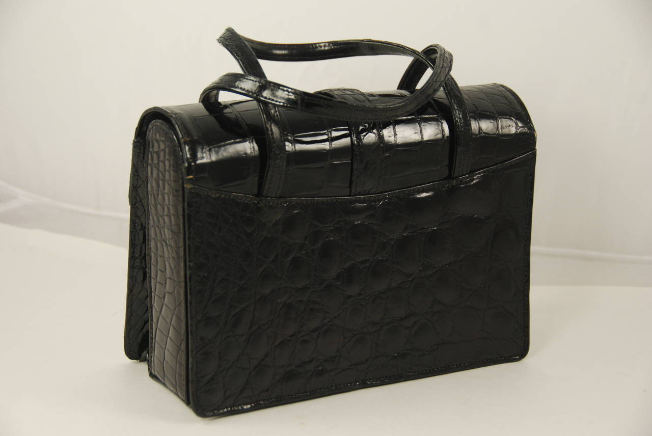 Black alligator handbag made in France and retailed by Saks FIfth Ave. Dating from the 1970s this bag is in great condition. The skins are glossy  and there is little signs of wear on the bag. Inside is lined in black leather and there is a zipper