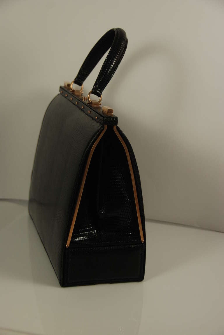 This is the height of elegance, a beautiful black lizard bag with a false bottom so you can carry your jewelry or cash and no one knows it is there but you. The main section of the bag opens by two brass clasps on the top that work well and close
