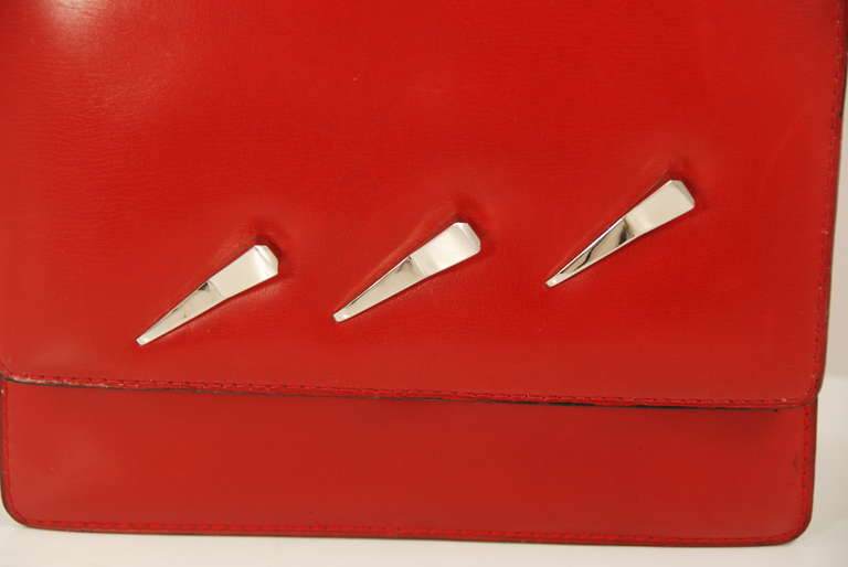 Red leather Pierre Cardin handbag made in Paris in either the late 1960s or early 1970s. The decorations on the front are what appear to be three horse nails.Bag closes via a pin clasp that works well and bag closes securely. Inside is lined in