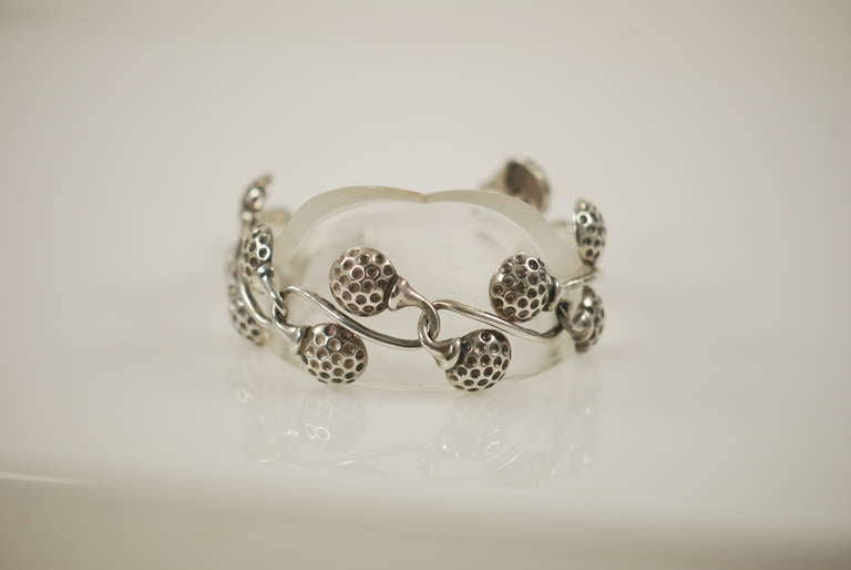 Angela Cummings sterling silver bracelet with a gold theme.  Each link has two golf balls sitting atop the golf tee. Closure is by a hook that works into the design. Bracelet has great texture and dimension with the contract between the smooth tees
