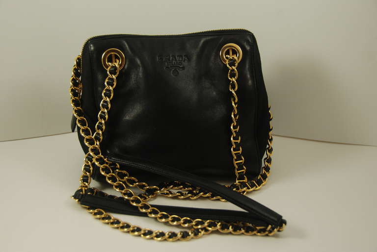 Prada black leather should bag made of butter soft leather. There is a double shoulder chain done in gold with black leather woven through the chain and black leather shoulder cushions. The sides and the bottom of the bag are done
in the Prada